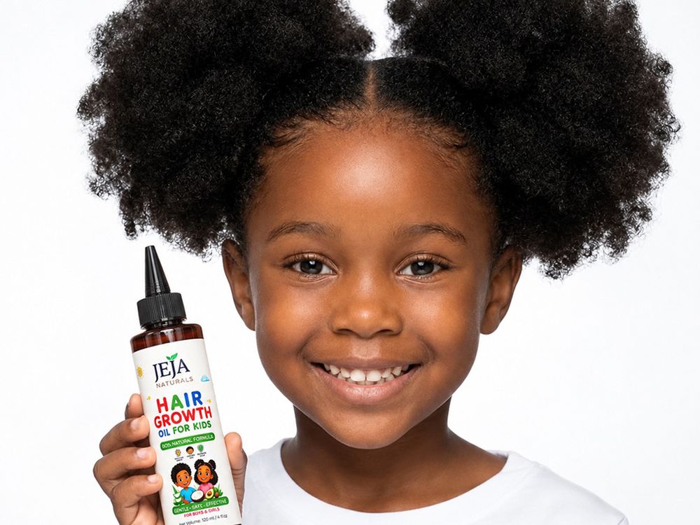 Smiling girl with afro puffs holding a bottle of JEJA Naturals Hair Growth Oil for Kids
